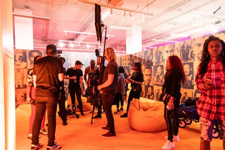 A film crew and guests at a bright orange activation set